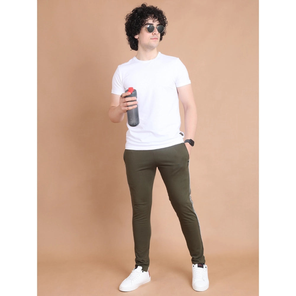 Person wearing a white t-shirt, green pants, and sunglasses holding a water bottle on a beige background