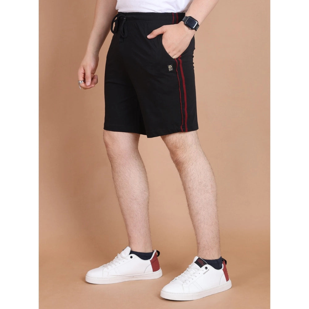 Person wearing black shorts with a red stripe and white sneakers on a brown background