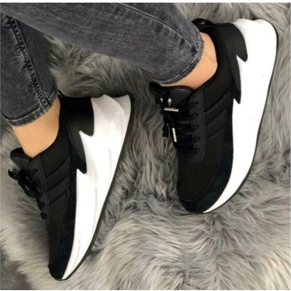 Black and white sneakers worn on a gray furry surface